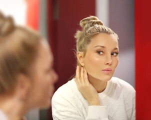 woman looking in the mirror in the bathroom and taking care of her skin.Applying the cream..Magic anti-aging cream.