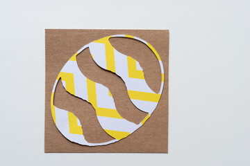 oval paper shape with wavy stripes on brown cardboard square
