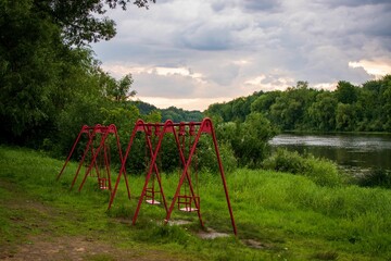 Obraz na płótnie Canvas Swings on the river bank surrounded by vegetation and grass
