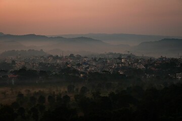 Greenery field with cityscape view of Hamirpur, Himachal Pradesh at sunset in a mist, India