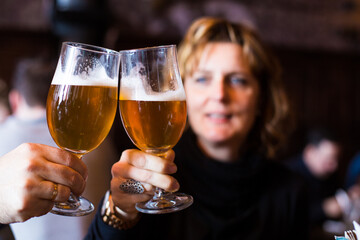 Adult couple having beer toasting in a restaurant.