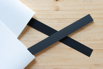 folded bristol board and black paper stripes on a wooden surface - obrazy, fototapety, plakaty