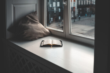 Open bible on windowsill, city view, morning prayer