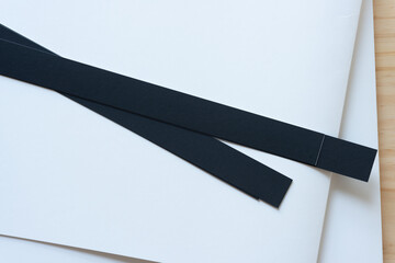 two black paper stripes on bristol board on wood - obrazy, fototapety, plakaty