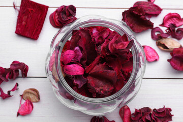 Aromatic potpourri of dried flowers in glass jar on white wooden table, flat lay