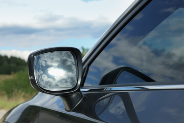 Fototapeta premium New black modern car outdoors, closeup of side rear view mirror