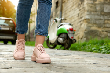 Woman in stylish sneakers walking on city street, closeup. Space for text