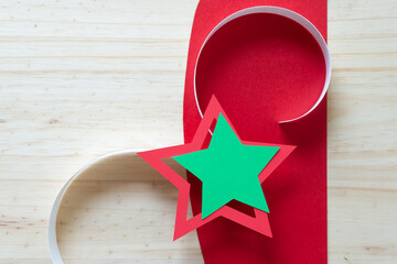 green and red paper star with curly paper tails on paper and wood