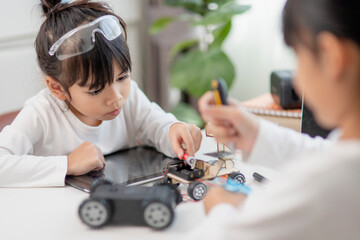 Two Asian students learn coding robot cars and electronic board cables in STEM, STEAM, mathematics engineering science technology computer code in robotics for kids concepts.