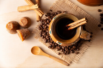 Authentic homemade mexican coffee (cafe de olla) served in traditional handmade clay mug (Jarrito de barro) on rustic wooden table.