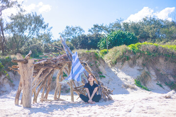 Fototapeta na wymiar 小屋の前に座りビーチを楽しむ女性