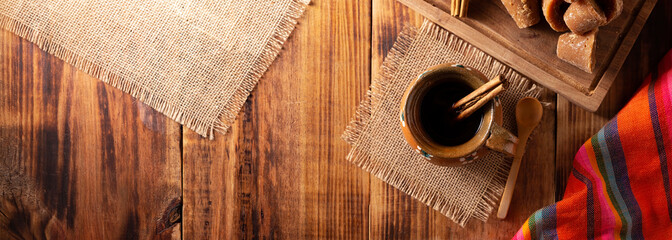 Authentic homemade mexican coffee (cafe de olla) served in traditional handmade clay mug (Jarrito de barro) on rustic wooden table.