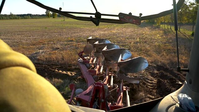 Farmer plowing the end of the field with reversible plough, view from tractor