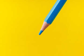 Colored pencil close-up with selective focus on the stylus and a blurred yellow background. Copy...