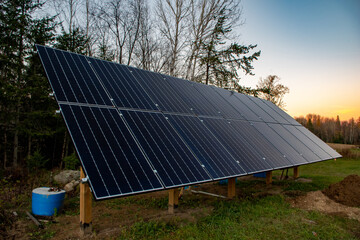 Newly constructed PV solar panel array against background of trees and blue sky, Ontario, Canada