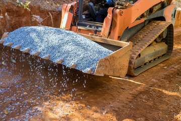 An excavator bucket rakes in crushed stone the excavator is picking up a full bucket of gravel