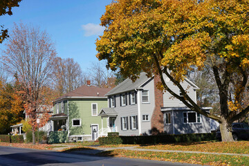 Fototapeta na wymiar Suburban residential street with bright fall colors and middle class houses with aluminum siding