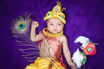 newborn baby boy in krishna dressed with props from unique perspective in different expression