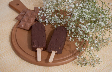 Chocolate posicle on the table with white flowers around
