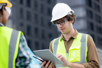 Fototapeta premium Young man and woman is architect planning and inspector project and looking digital tablet at construction site, engineer male and female working and examining for development real estate.