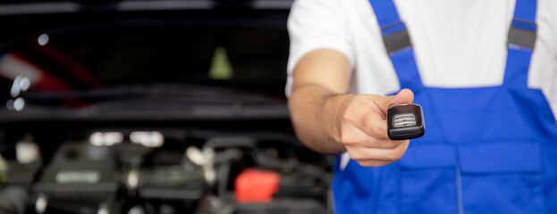 Closeup hands of mechanic giving key after repair car at garage, auto service, insurance with...