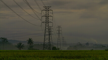 High-voltage electricity tower built in rice fields with sunrise sky