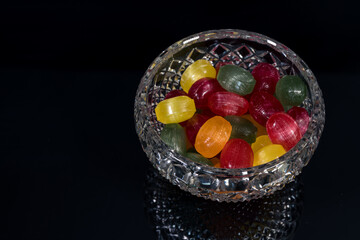 hard candies fruit flavor in various colors (red, green, yellow, orange), in a glass, crystal bowl,...