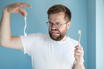 Man opts for a biodegradable bamboo toothbrush and despises the plastic brush. Eco concept.