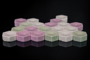 Fruit-flavored powder pastilles, powder lozenges, in three colors, green, white and red, scattered on a black background, sweets and candies arranged in abstract patterns, high sugar content