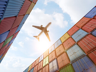 Cargo plane flying above stack of containers at container port - obrazy, fototapety, plakaty