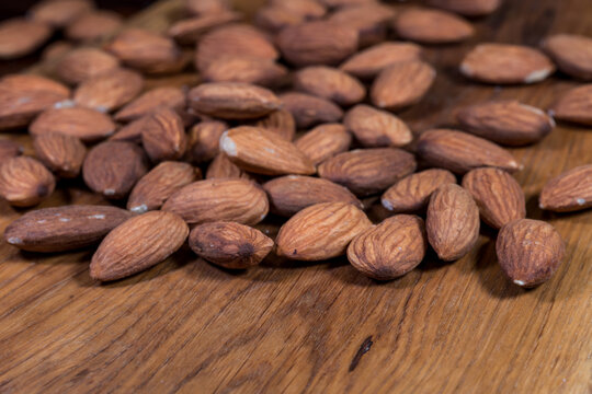 Whole Almonds, Scattered On A Wooden Board. Almond Fruit Seeds. Edible Raw, And Suitable For Preserves. Almonds Are A Valuable Source Of Micro And Macro Elements And Monounsaturated Fatty Acids.