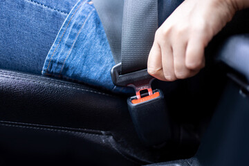 Close-up of a female driver fastens her seat belt before driving. safe travel concept