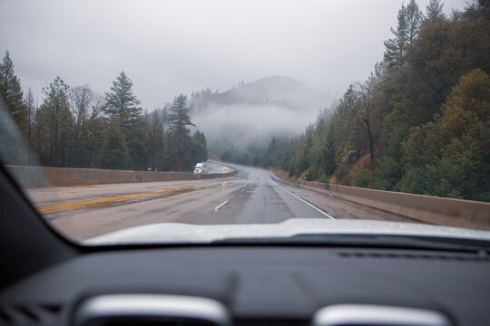 Driving on wet highway with fog on hills