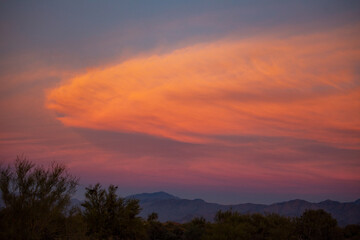 Pink and orange clouds over desert landscape at dusk