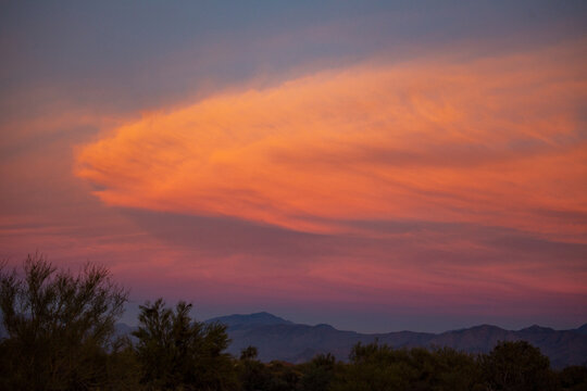 Pink and orange clouds over desert landscape at dusk
