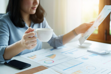 A portrait of an Asian businesswoman showing a happy smiling face holding a cup of coffee during a break