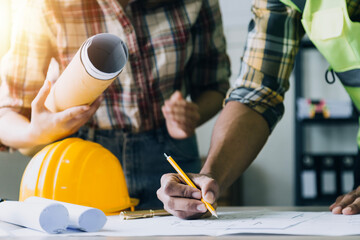 Construction engineer working at blueprint to build large commercial buildings in office. Engineering tools and construction concept.