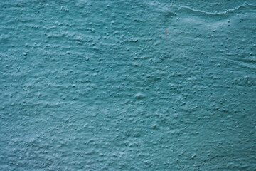 Abstract texture of rough uneven relief plaster in blue-green color.