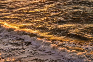 Sea wave and golden sunset reflection, Pacific Ocean, California, USA, close-up. Beautiful scenery and background