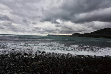 stormy weather at sea with low mountains and waves