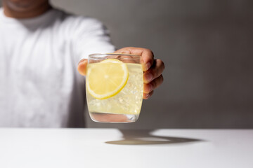 Man holding a glass of lemonade juice on white table. Drinking for detox and Antioxidant. Cold beverage for web banner.