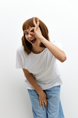 vertical photo of a funny, cute woman showing an ok sign near her eye while leaning towards the camera