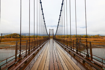 Obraz premium suspension bridge across the river, altai view dilapidated old bridge crossing
