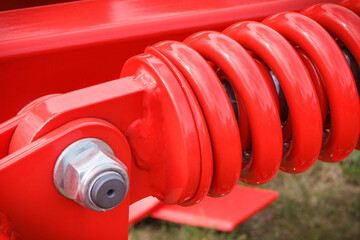 Hard red spring made of steel. Part of big industrial or agricultural machine