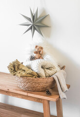 A straw basket with cozy blankets on a wooden bench, a Christmas star on the wall in the interior of the children's room