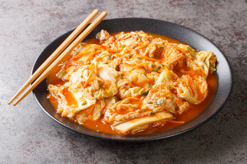 Kimchi is a traditional Korean side dish of salted and fermented vegetables, such as napa cabbage, carrot and Korean radish with spices closeup on the plate on the table. Horizontal