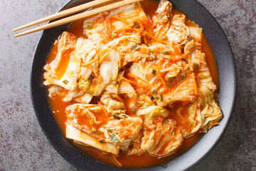 Close up Korean food, Kimchi cabbage in a black dish on a table. Horizontal top view from above