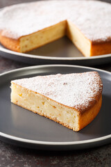 Yogurt cake or gateau au yaourt is a classic French baked good with icing sugar closeup in a plate on a table. Vertical