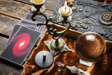 Tarot cards, crystal ball and book of magic on the old fortune teller desk table background. Future reading concept.