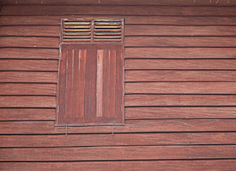 The walls of a red wooden house with windows are the ancient houses of Thailand.